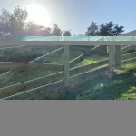 A farm wooden fence constructed from vertical planks, showcasing a natural wood finish and sturdy design.