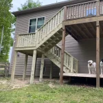 A wooden deck featuring stairs, surrounded by greenery, inviting for relaxation and outdoor gatherings. Two pit bulls are on the bottom level.