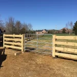 A farm wooden fence constructed from vertical planks, showcasing a natural wood finish and sturdy design, and a metal gate.
