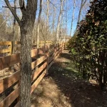 A farm wooden fence constructed from vertical planks, showcasing a natural wood finish and sturdy design.