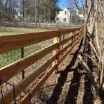 A farm wooden fence constructed from vertical planks, showcasing a natural wood finish and sturdy design, and metal meshing.