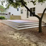 A wooden deck featuring stairs, surrounded by greenery, inviting for relaxation and outdoor gatherings.