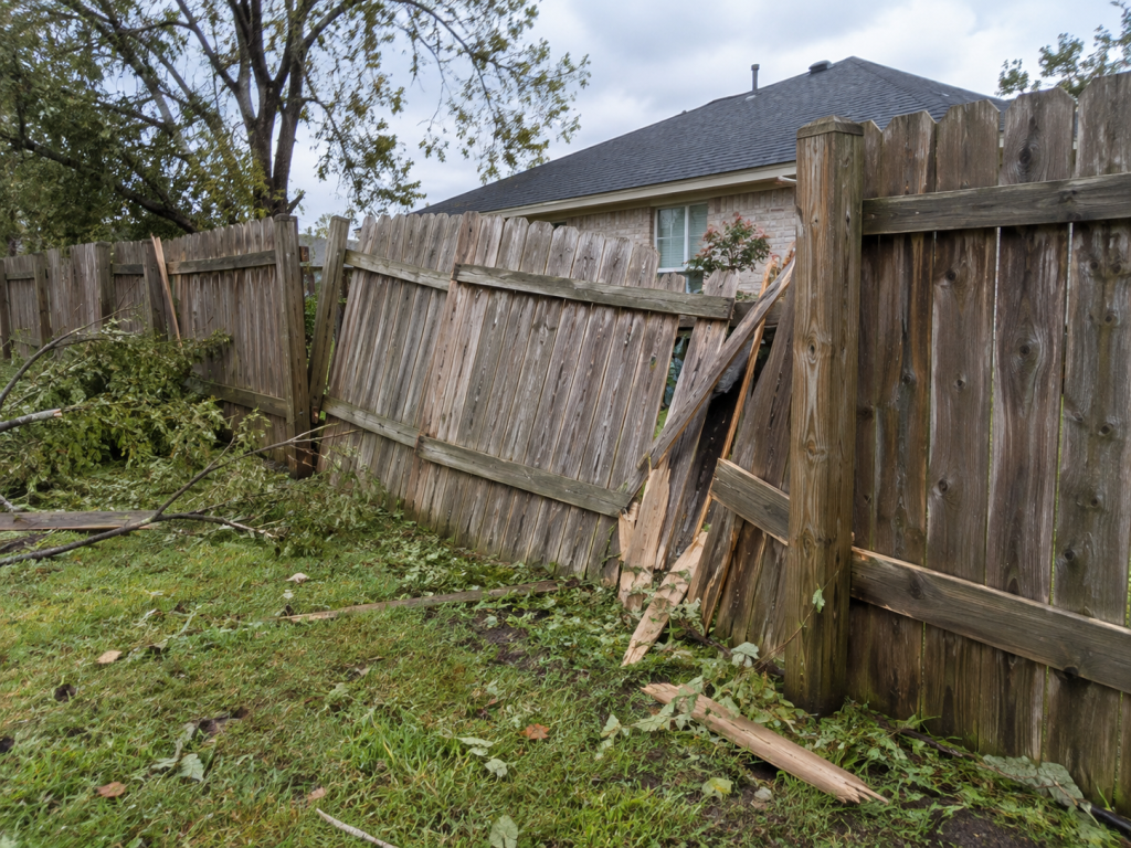 Wood fences with a leaning section and broken boards after strong winds.